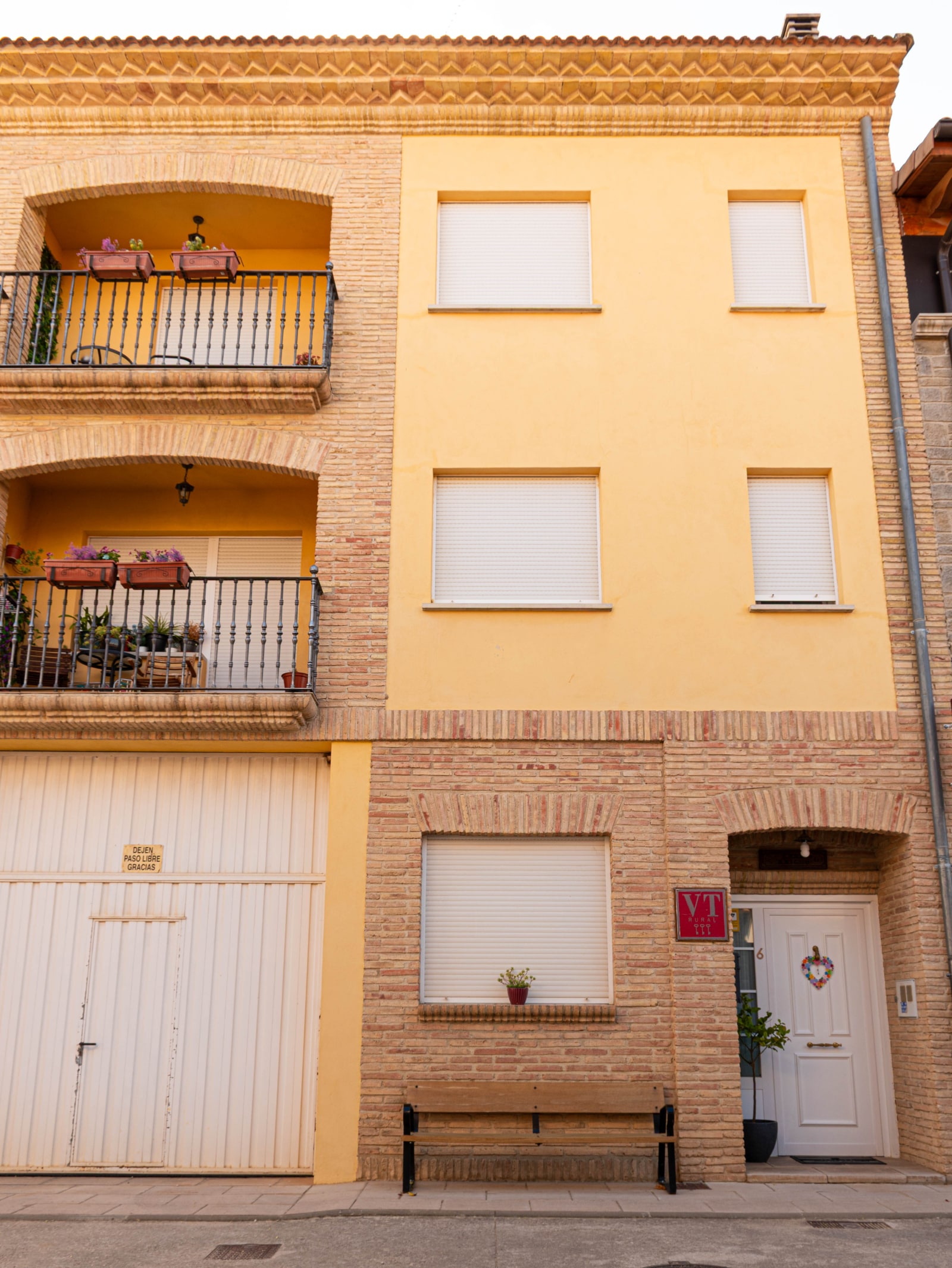 Fachada de Casa Raichu · Balcones, banco y entrada en el número 6
